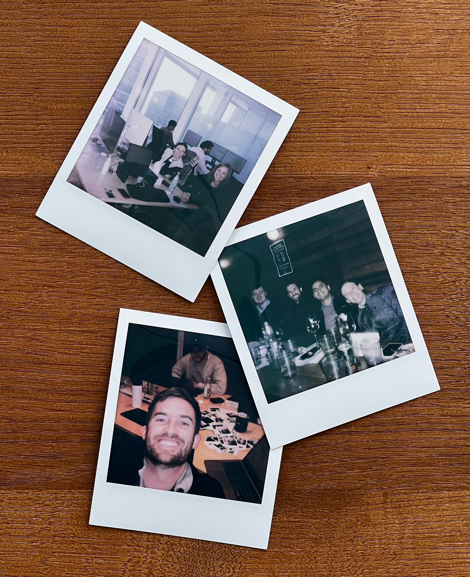 Three polaroid prints spread on a table, each showing teammates working and smiling.