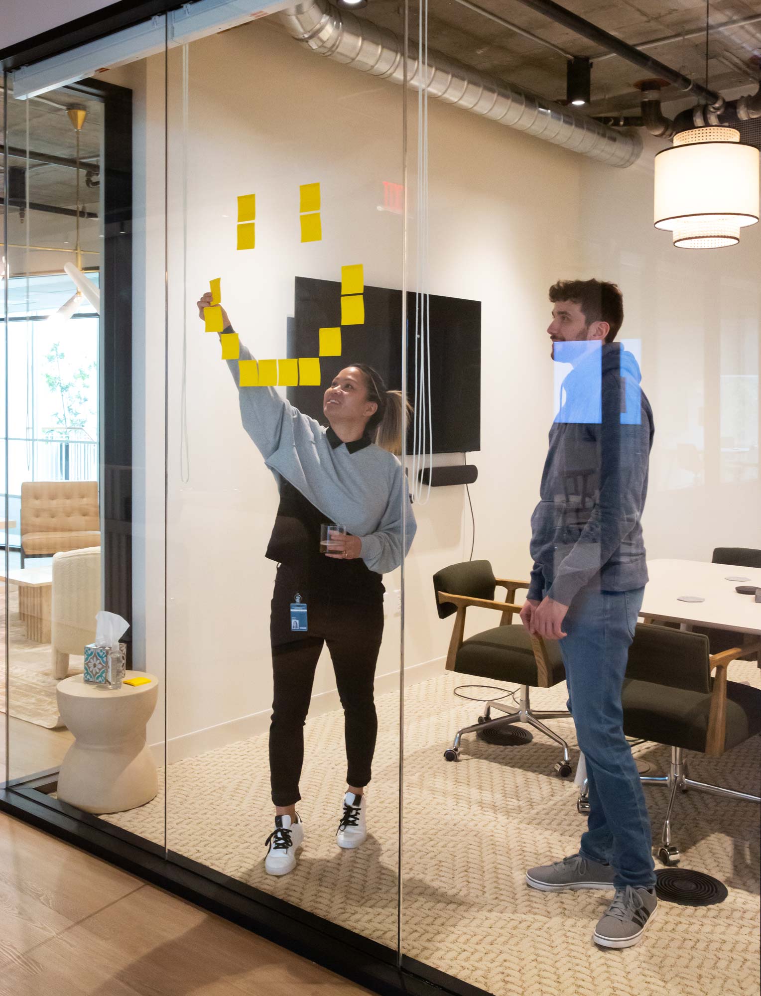 Teammate at Column applies sticky notes to glass in shape of a smiley face.